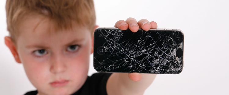 Kleiner Junge mit einem defekten Smartphone in der Hand